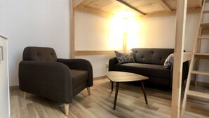 Ein gemütliches Wohnzimmer mit einer Couch, einem Sessel und einem kleinen Holztisch.