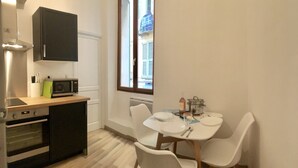Eine kompakte Küche mit Mikrowelle, Backofen und einem Esstisch mit Stühlen.