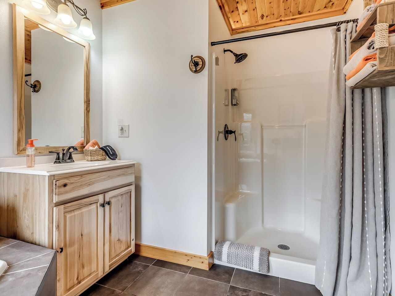A bathroom with a wooden vanity, a glass shower enclosure, and a towel rack.