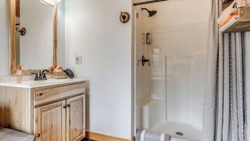 A bathroom with a wooden vanity, a glass shower enclosure, and a towel rack.