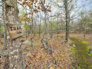 A wooden trail sign in a forested area with a path leading through the woods. - Romantic Lakeview Treehouse with Jacuzzi Tub & Private Deck (Stigler)