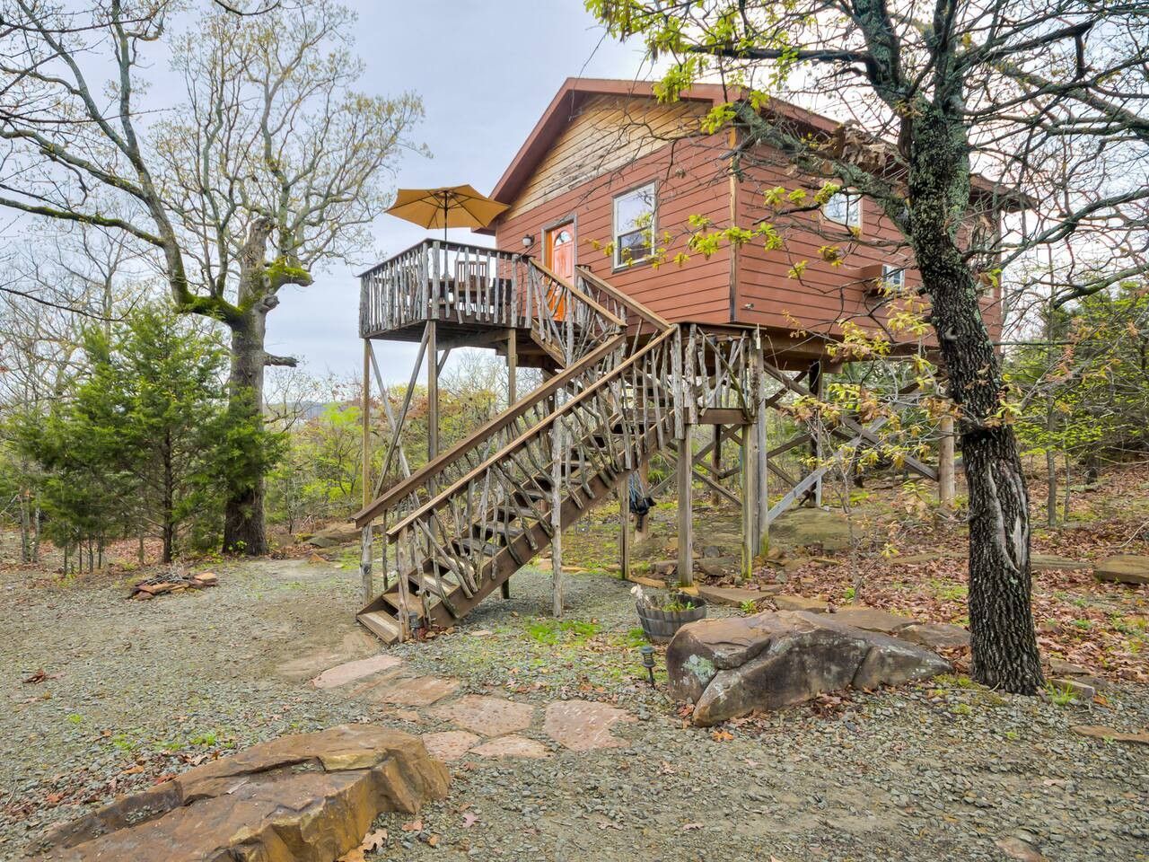 A wooden house with a wooden staircase leading to a deck.