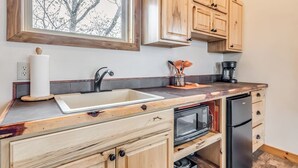 Una cocina con armarios de madera, horno integrado y ventana sobre el fregadero.