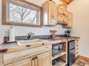 Une cuisine avec des meubles de rangement en bois, un four encastré et une fenêtre au-dessus de l’évier.