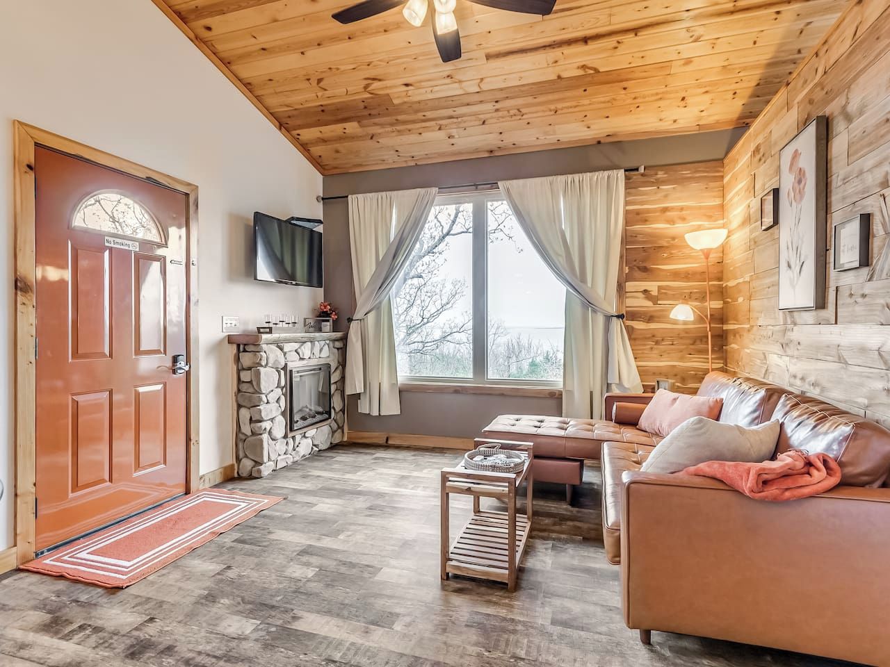A cozy living room with a fireplace, a sofa, a coffee table, and a television mounted on the wall.