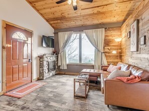 Una sala de estar acogedora con chimenea, un sofá, una mesa de centro y un televisor montado en la pared.