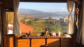 A room with a wooden floor, a blue yoga mat, a wooden desk with a statue, a bowl, and a small plant. - Casa Abacate (Imbituba)