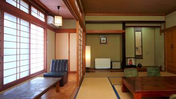 A traditional Japanese room with tatami flooring, a low table, a cushioned bench, and sliding doors.