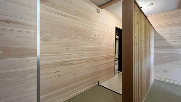 Un intérieur moderne avec des murs lambrés et une porte visible donnant sur une autre pièce.