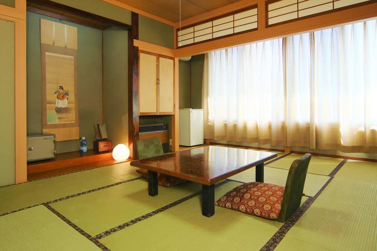 Ett traditionellt japanskt rum med tatamimattor på golvet, ett lågt bord och skjutdörrar.