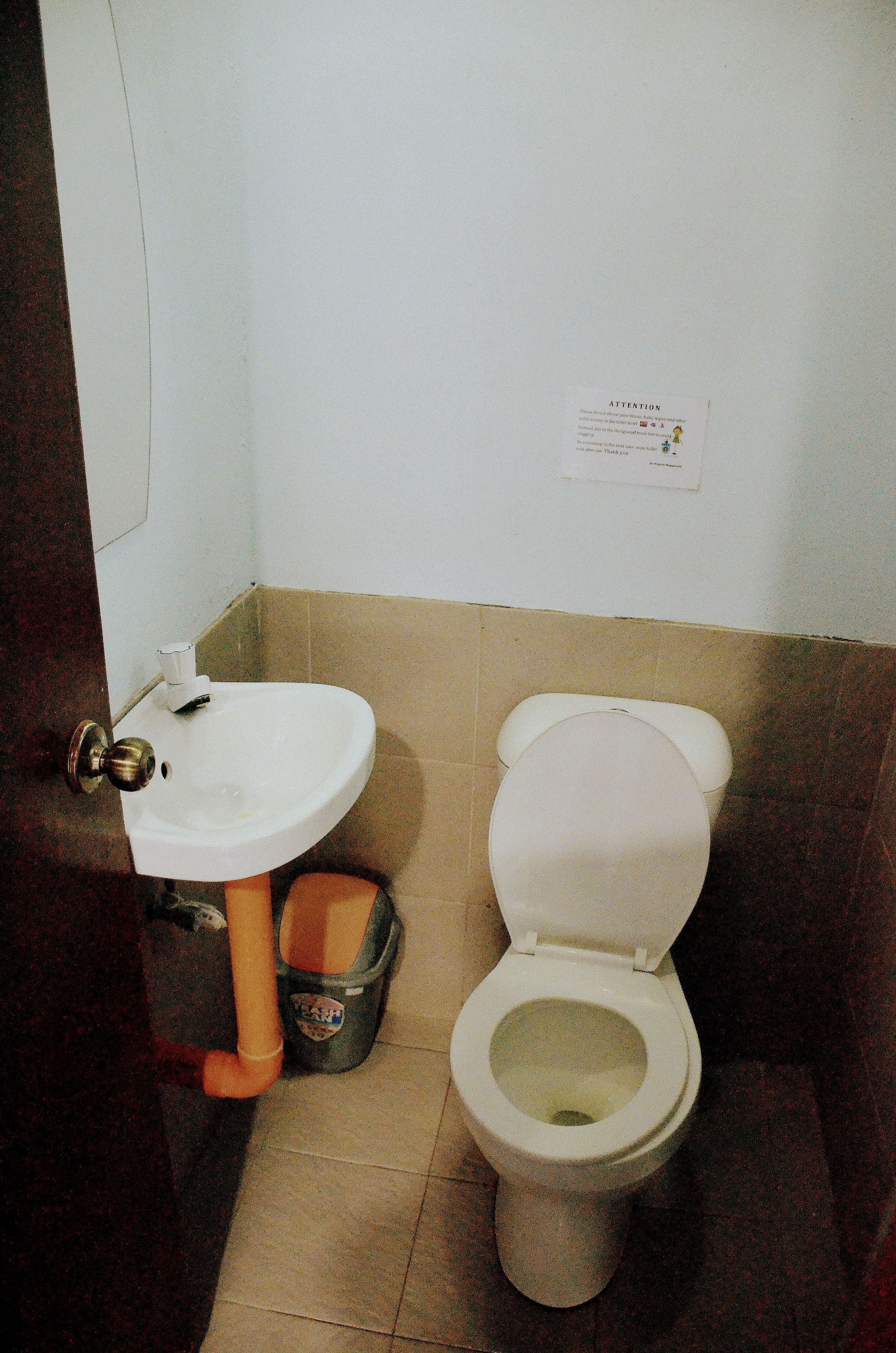 A small bathroom with a sink, toilet, and trash can.