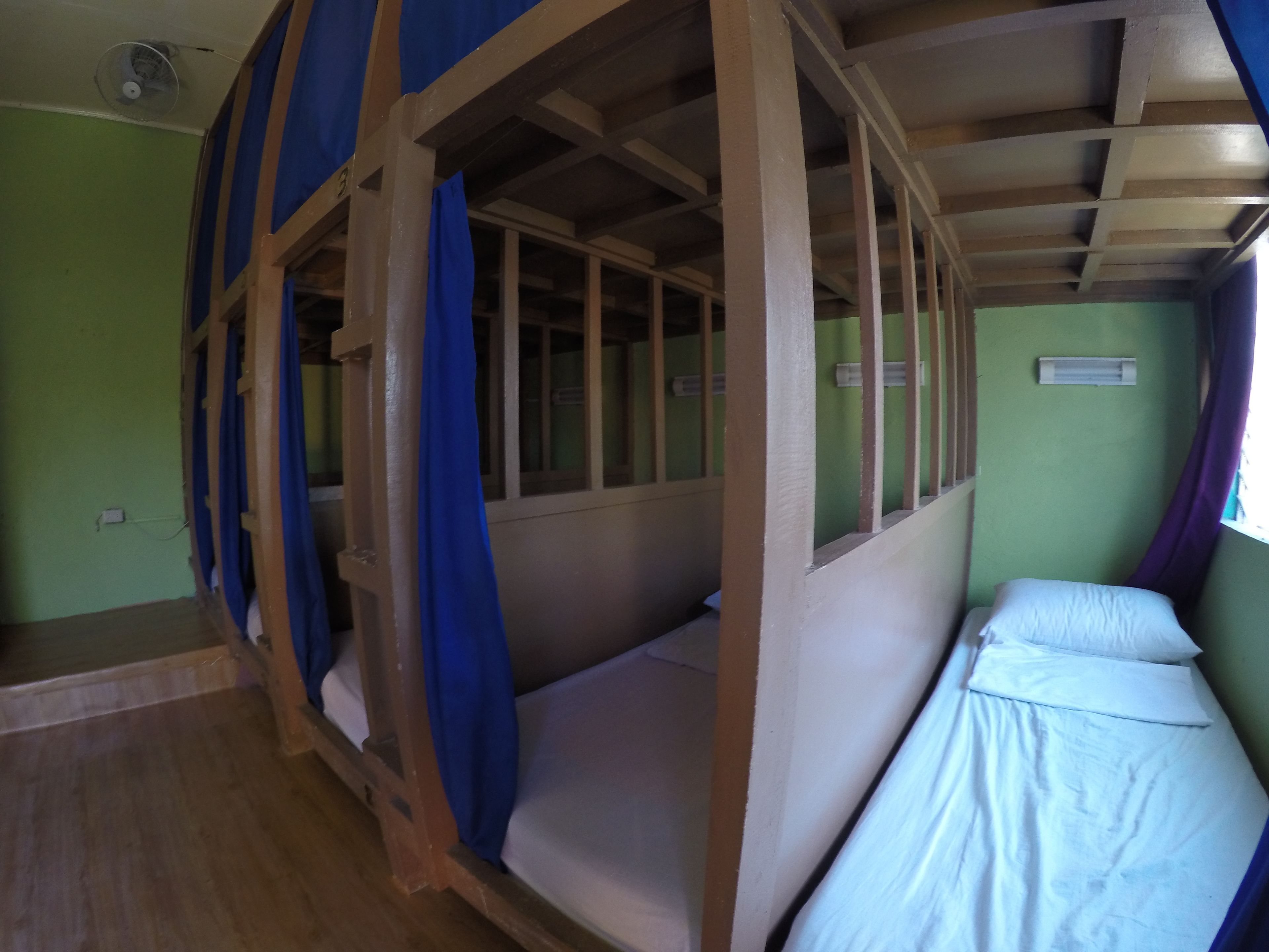 A room with bunk beds, a fan, and a window with curtains.