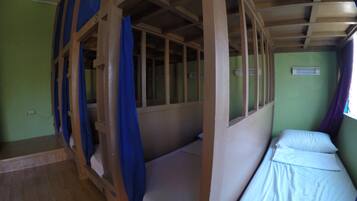 A room with bunk beds, a fan, and a window with curtains.