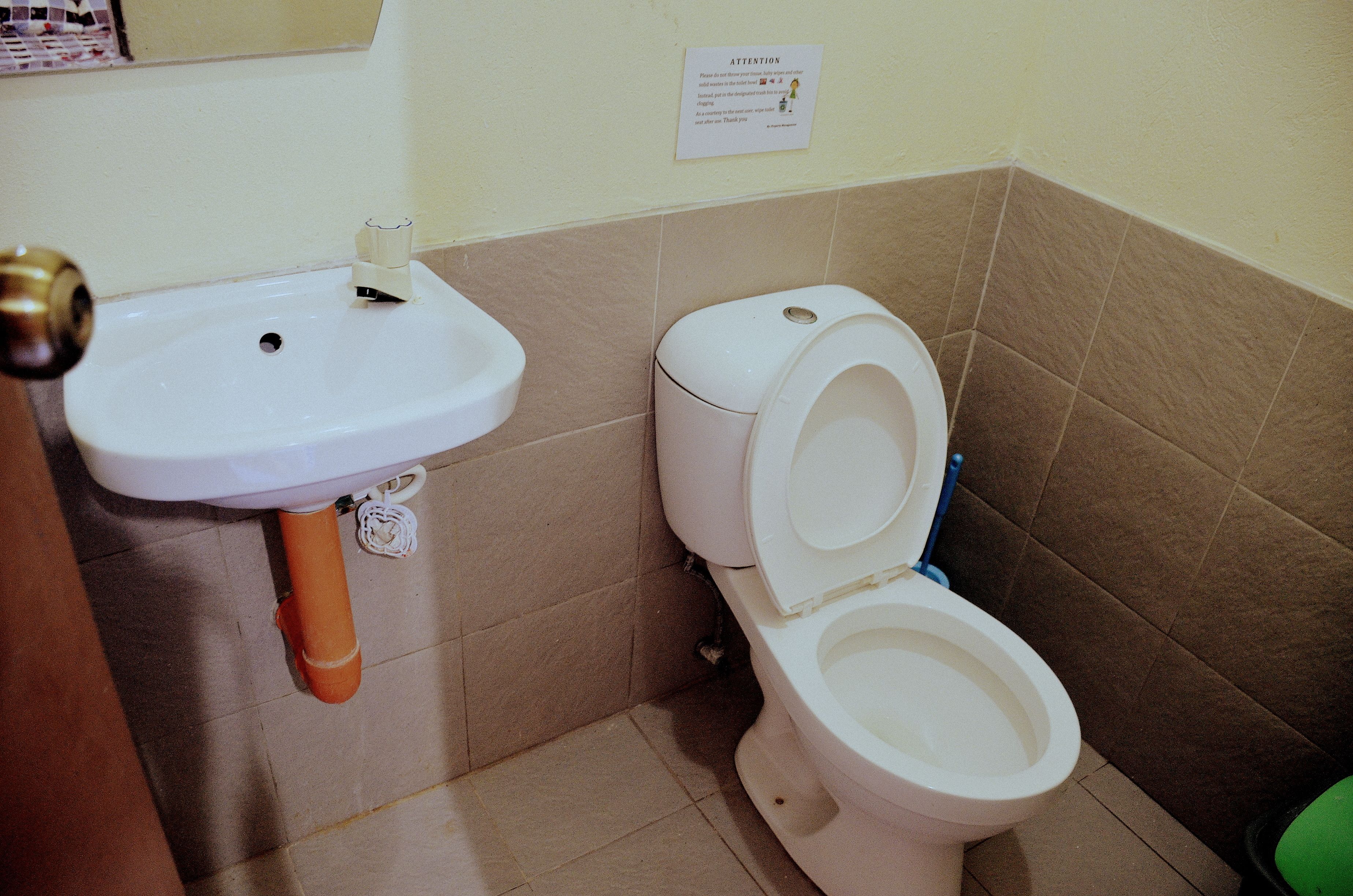 Een badkamer met een wastafel, toilet en een bordje aan de muur.