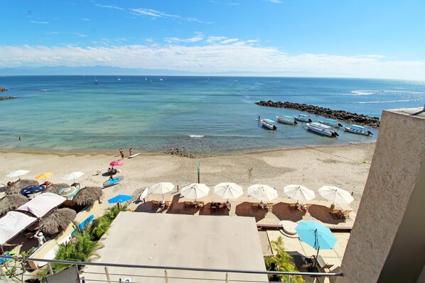 En la playa, arena blanca, sombrillas, toallas de playa