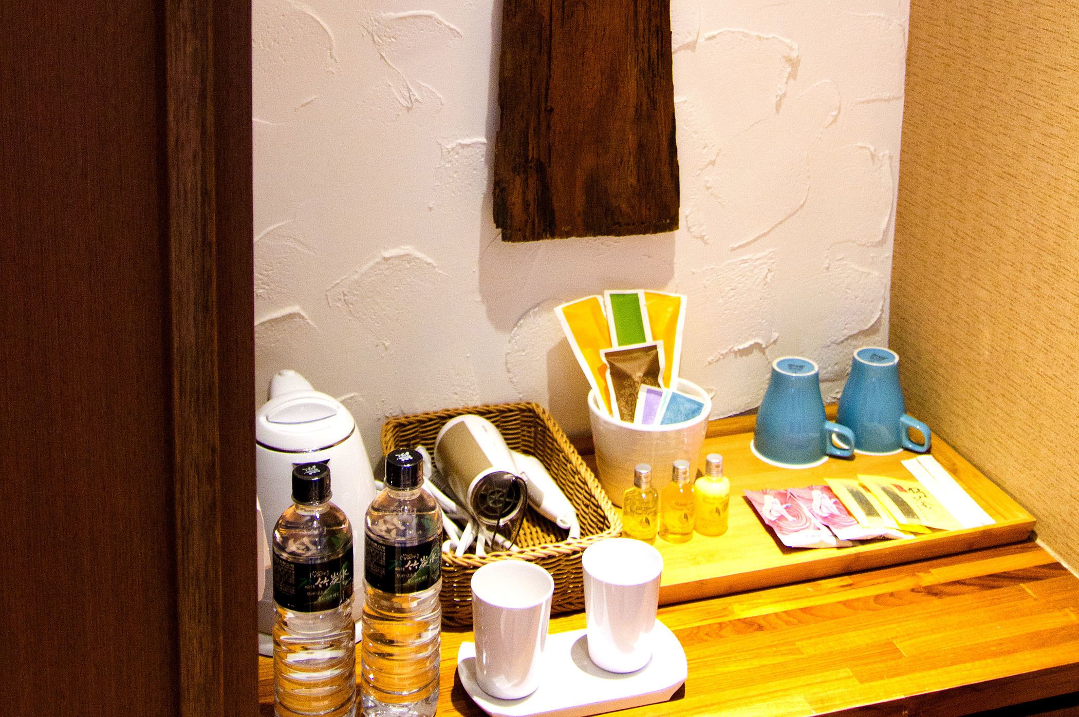A breakfast setup with a coffee maker, bottles, cups, and a basket.
