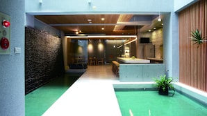 Un hall d’hôtel moderne avec un comptoir d’accueil, un espace salon et un chemin recouvert d’une moquette verte.