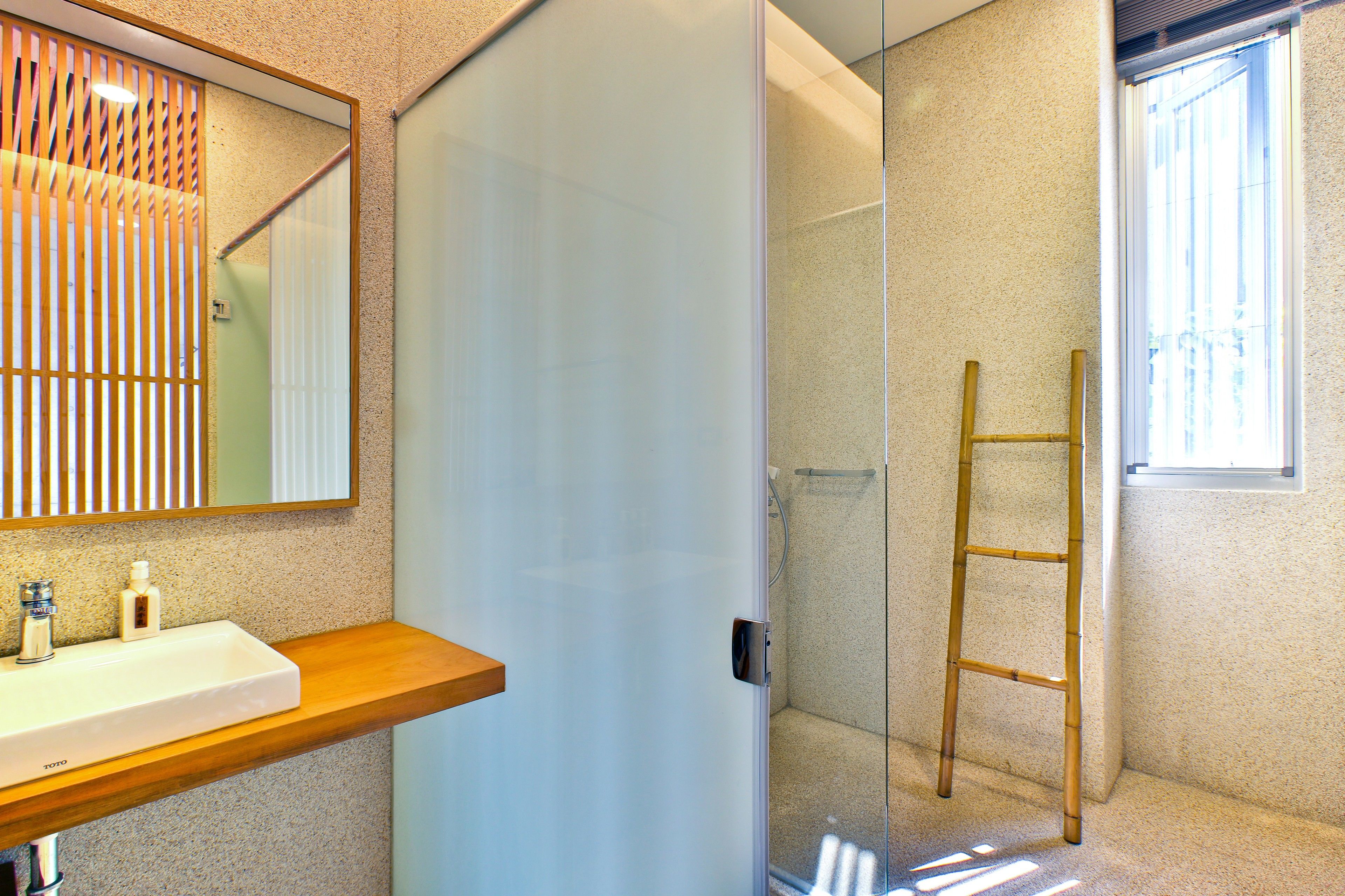 Une salle de bain moderne avec un meuble-lavabo en bois, une cabine de douche en verre et une échelle pour accéder à la douche.