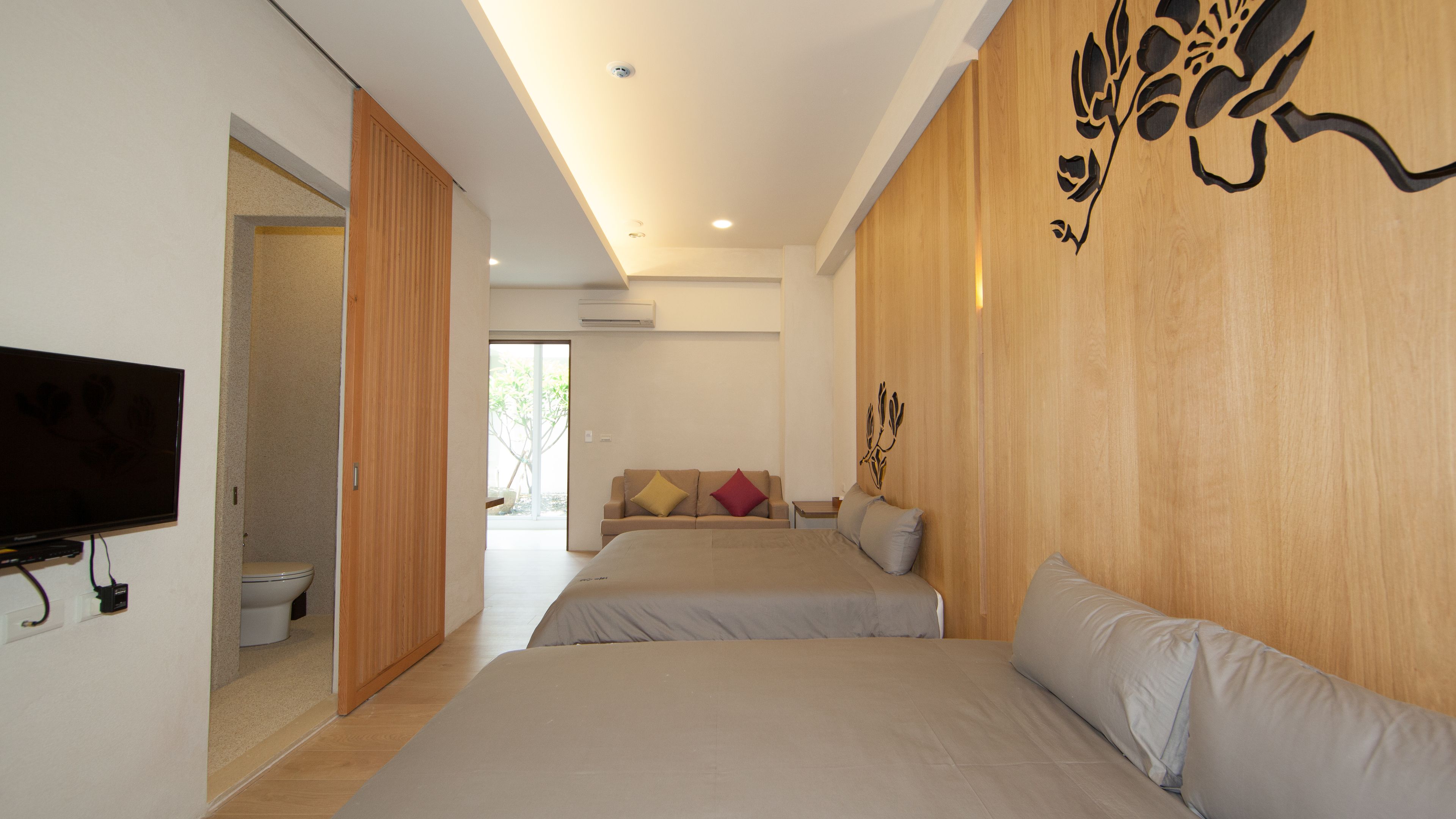 A modern hotel room with two beds, a TV, and a wooden accent wall.