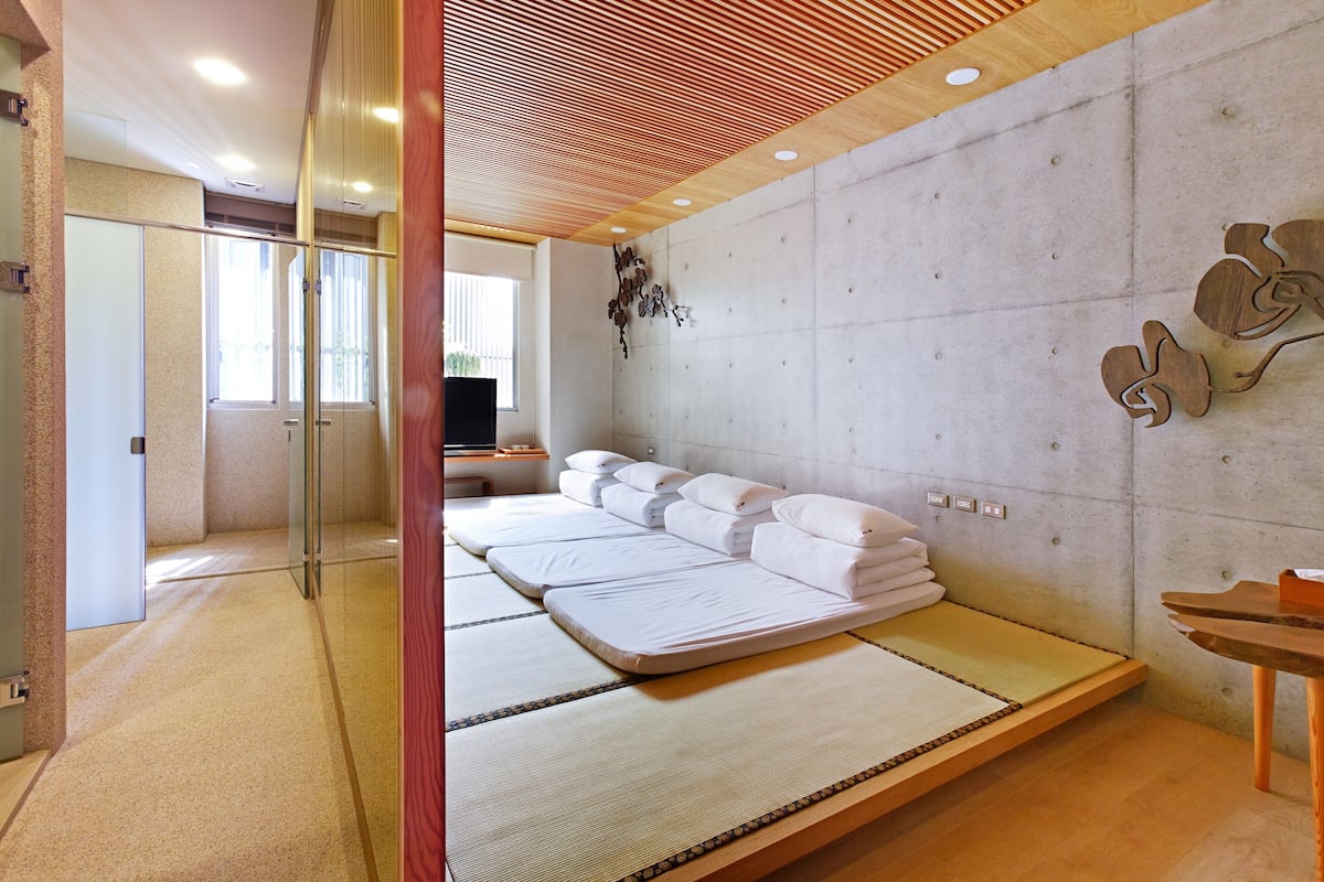 Un moderno spa con esteras de tatami, techo de madera y una gran pared de piedra.