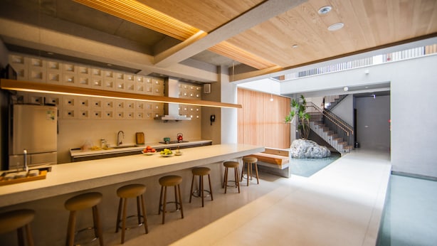 Une cuisine moderne dotée d’un long comptoir, de tabourets de bar et d’un escalier menant à un niveau supérieur.