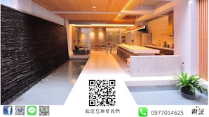 Une cuisine moderne avec un îlot central, un plafond en bois et un mur foncé à la texture marquée.