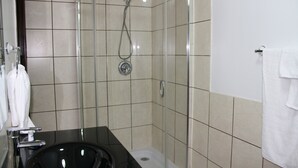 A modern bathroom with a glass-enclosed shower, a black sink, and white tiled walls. - IACC Centers - Hotel Downtown Windsor (Windsor)