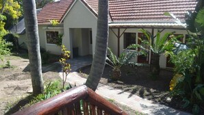 A house with a tiled roof, surrounded by lush greenery and a wooden deck. - Cycad Lodge (East London)