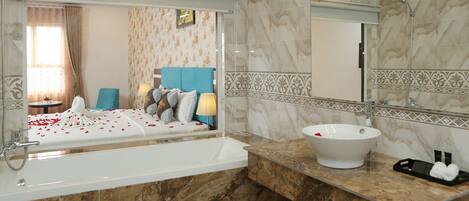 Un baño moderno con una bañera grande, un lavabo blanco y un espejo sobre él.