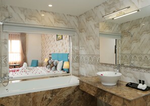 A modern bathroom with a large bathtub, a white sink, and a mirror above the sink. - The Mira Boutique Hotel (Ho Chi Minh City)