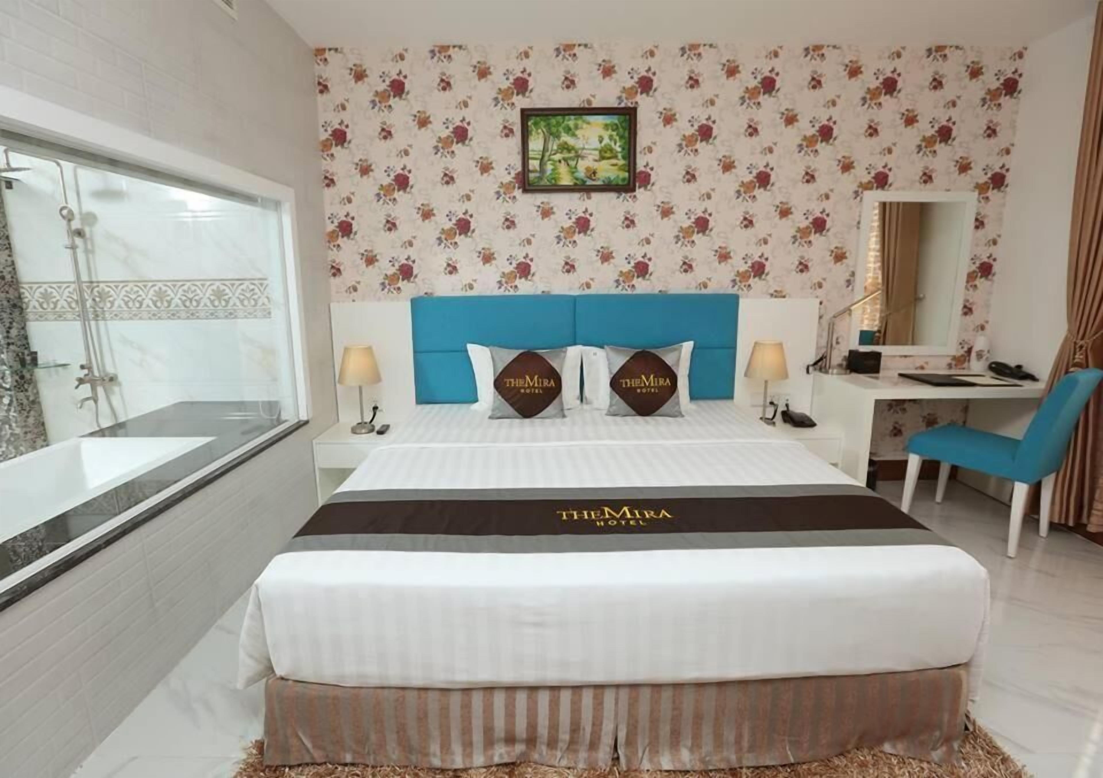 Hotellihuone, jossa on suuri sänky, työpöytä, tuoli, suihku ja kylpyammeella varustettu kylpyhuone.