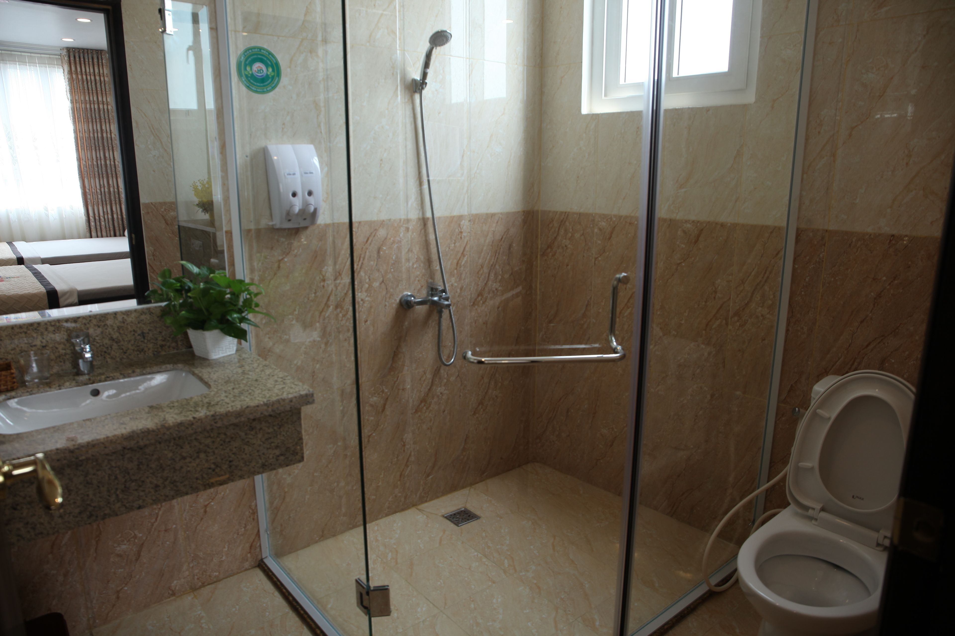 A bathroom with a glass-enclosed shower, a sink with a marble countertop, and a toilet.