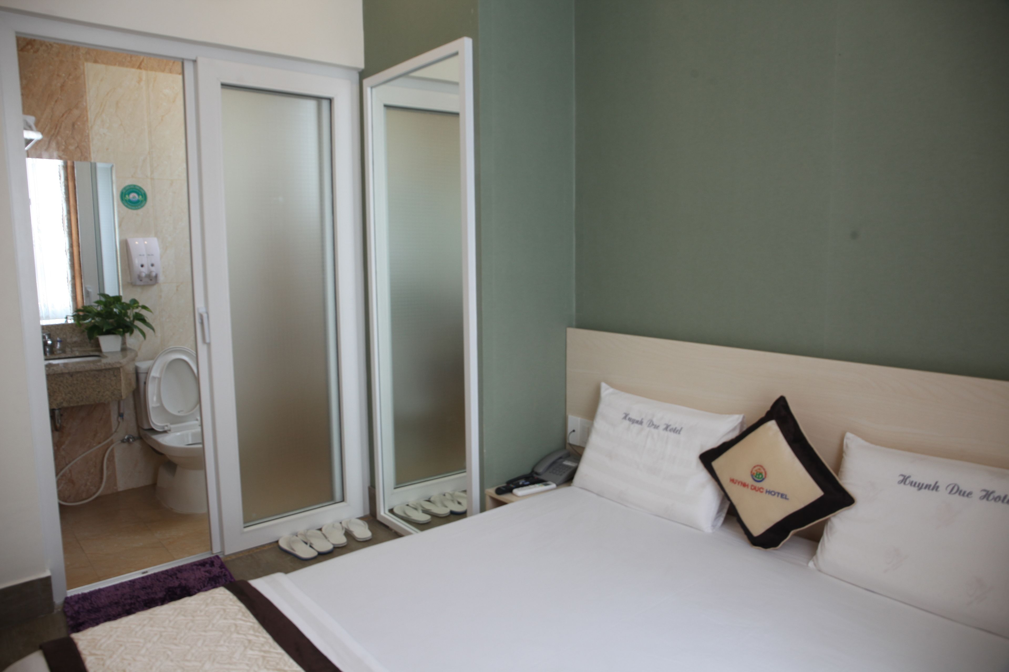 A hotel room with a bed, a bathroom, and a sliding door to the outside.