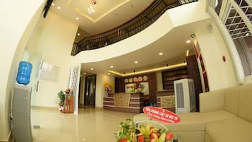 A hotel reception area with a reception desk, a staircase, and a water dispenser.