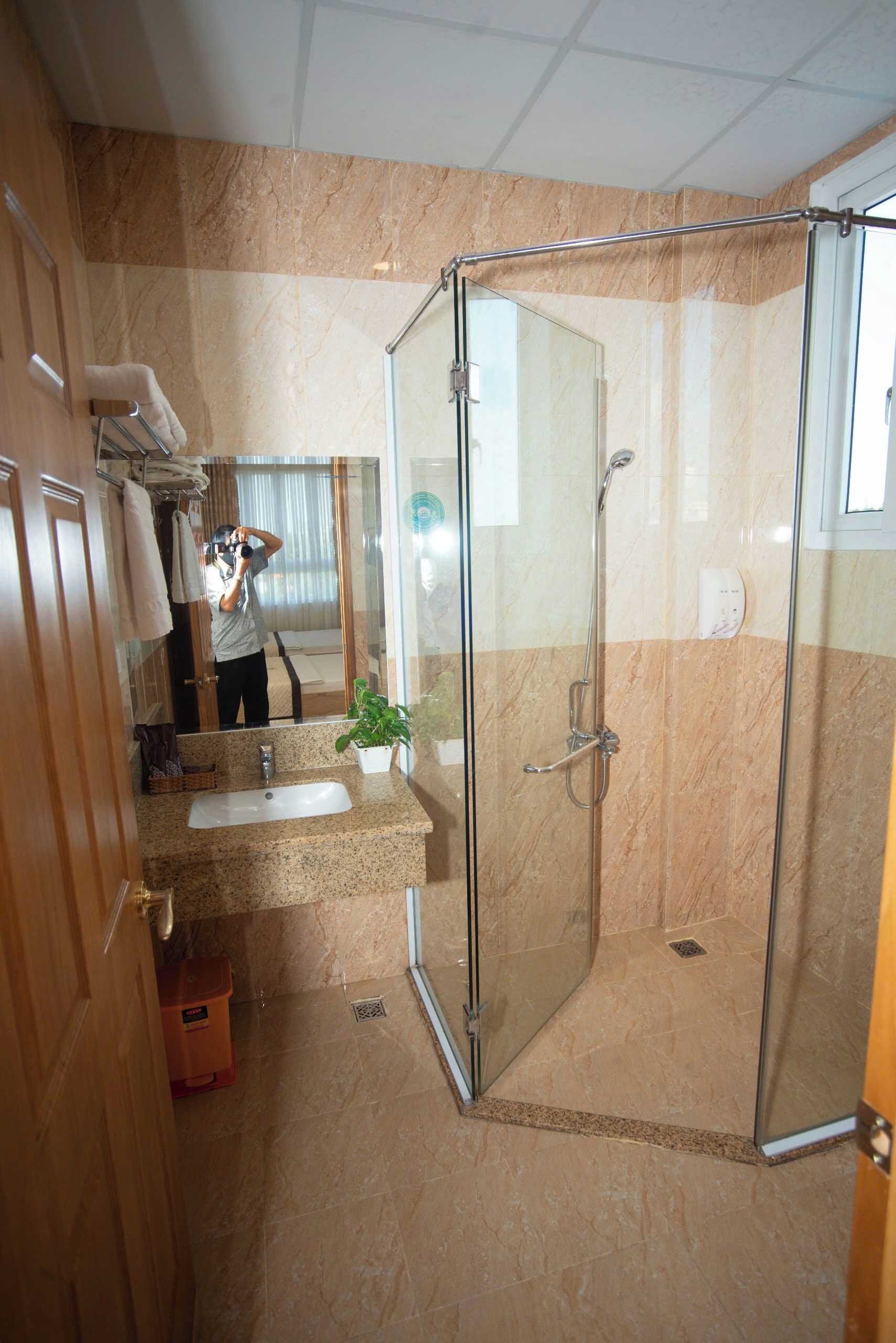 Une salle de bain avec une douche à parois de verre, un lavabo doté d’un plan de toilette en marbre et un miroir.