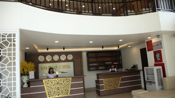 A hotel reception area with two reception desks, a staircase, and a large air conditioning unit. - Huynh Duc 2 Hotel (Cao Lanh)