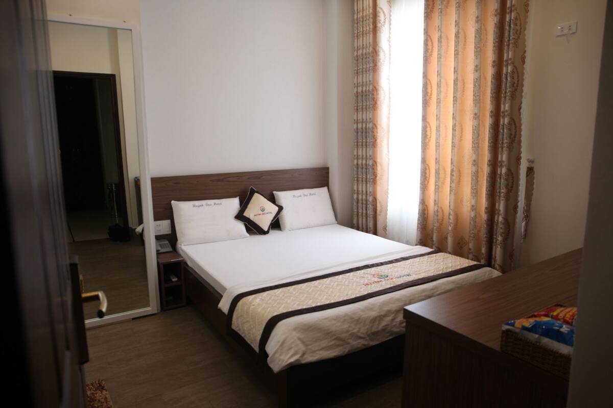 Une chambre d’hôtel comprenant un lit, une table de chevet et un bureau avec une chaise.