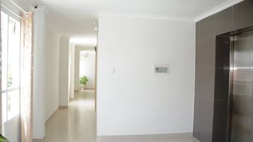 Un hall d’entrée spacieux et bien éclairé, avec un coin cuisine moderne doté d’un réfrigérateur en acier inoxydable.