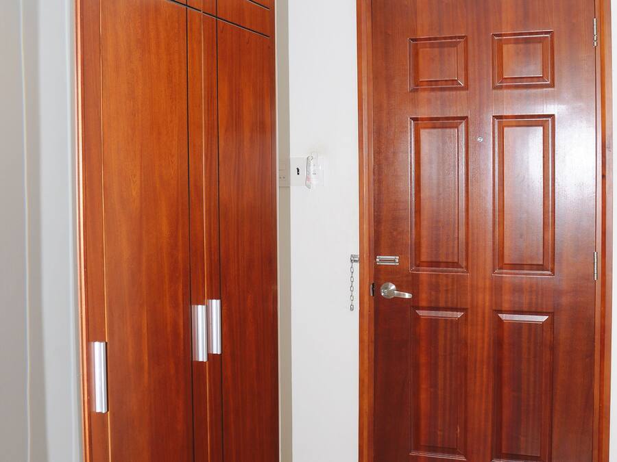 Una habitación con un armario de madera, una puerta de madera y suelo de baldosas.