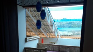 A room with a view of a beach, a staircase, and a bed with a purple bedspread. - Bahay Isla Sanctuario (Puerto Galera)