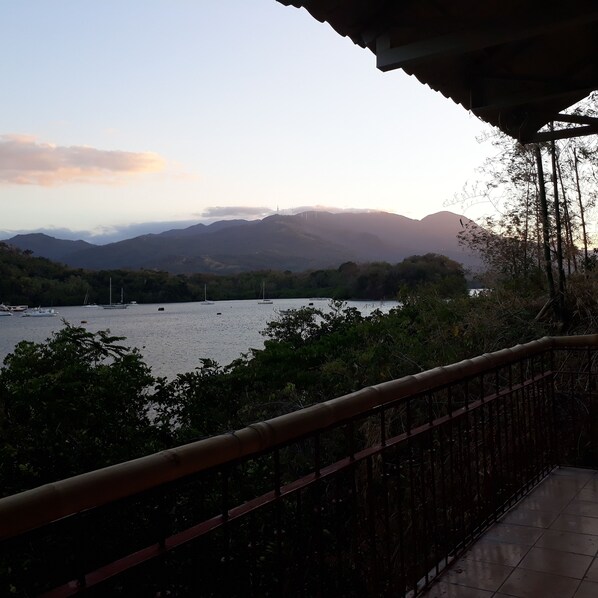 A balcony with a view of a lake, boats, and distant mountains.