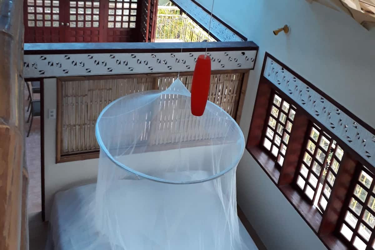 A room with a traditional architectural design, featuring wooden lattice windows and a balcony with a glass enclosure.