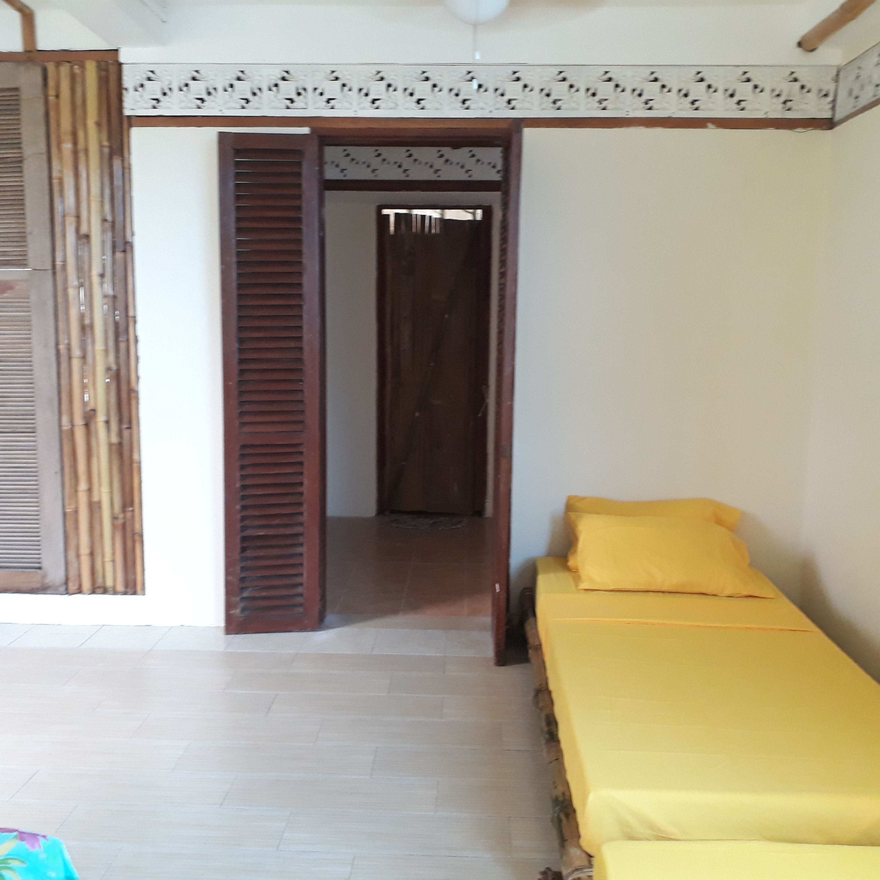 A room with a bed, a door, and a bamboo screen.