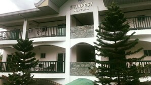 A hotel with a sign reading "SINPOST HOTEL" and multiple balconies with railings.