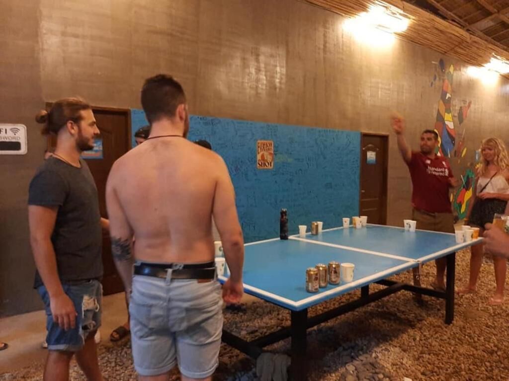 A room with a ping pong table, a blue wall, and a door with a sign.