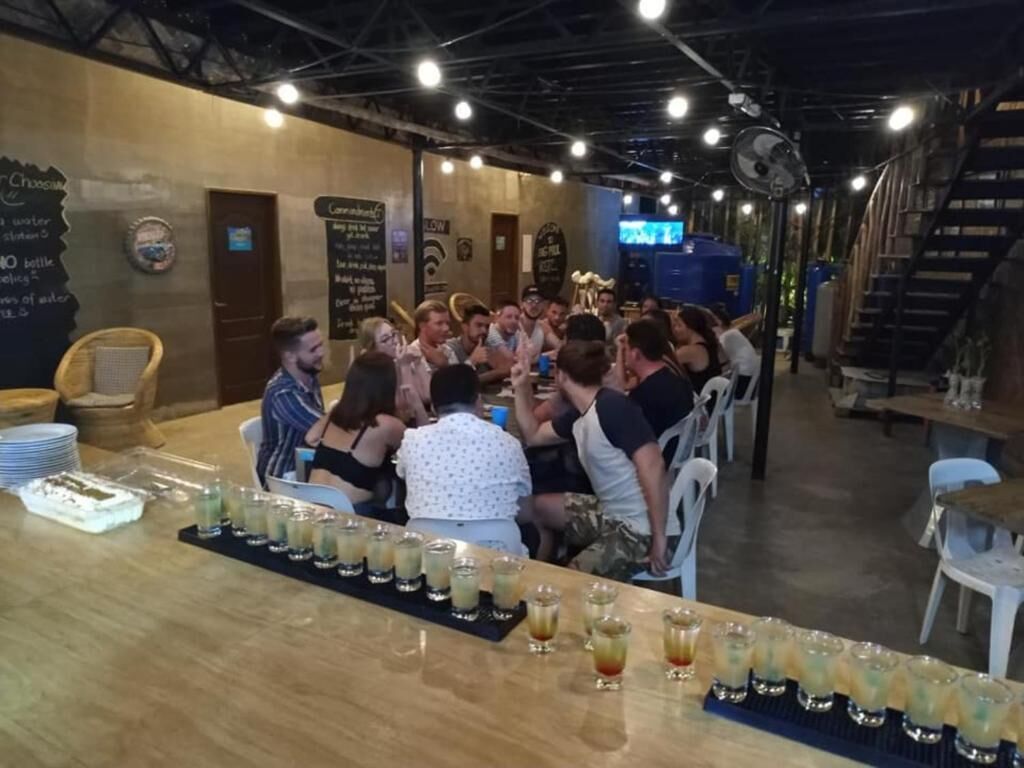 A bar area with a long counter displaying multiple glasses of a beverage, surrounded by patrons.