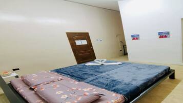 A bedroom with a bed, floral bedding, a door, and a wall with a picture.