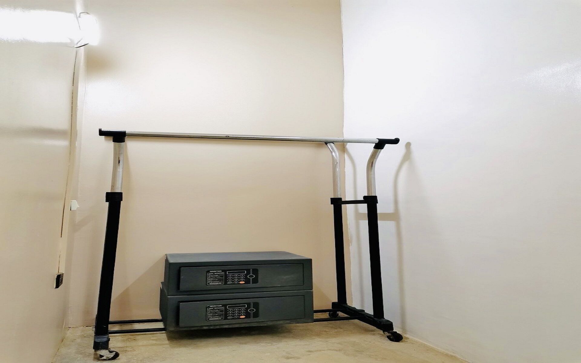 A corner room with a black metal rack against the wall and a small black cabinet.