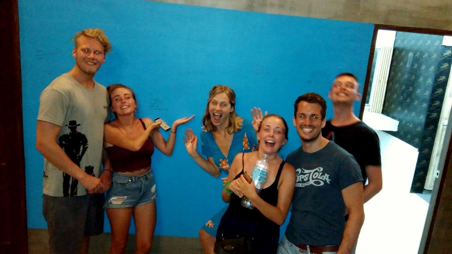 A group of people posing in front of a blue wall with a window to the right.