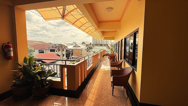 A corridor with a balcony, potted plants, and a fire extinguisher. - Mini Cost Apartment & Guesthouse (Chiang Mai)